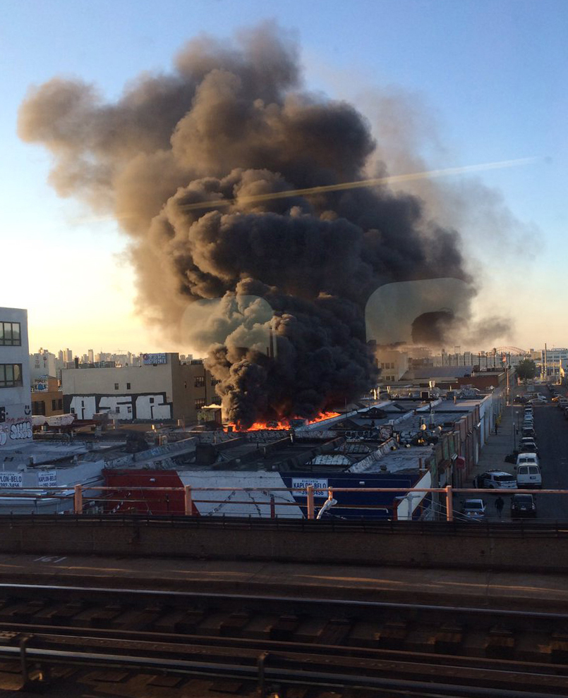 In this photo provided by Reena Karani, MD, MHPE, a warehouse fire rages in the Queens borough of New York, Wednesday, Aug. 3, 2016. Fire officials say over a hundred firefighters and emergency workers responded to 3-alarm blaze. (Reena Karani MD, MHPE via AP)
