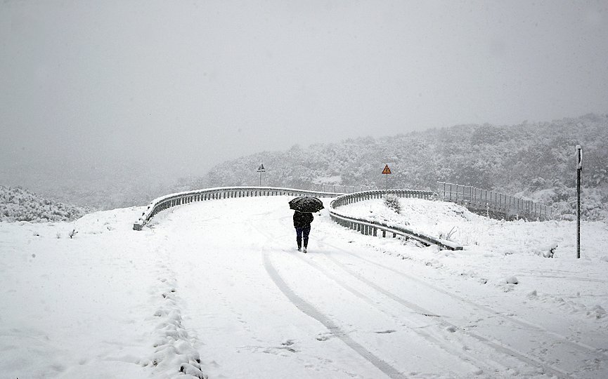 A woman passes a snow-covered bridge in Myrodafni village, near Ioannina city, northwestern Greece, Friday, Jan. 4, 2019. (AP Photo/Thanassis Stavrakis)