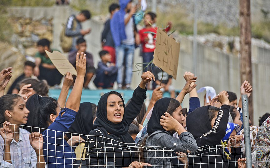 FILE- Refugees and migrants take part in a protest outside an overcrowded refugee camp on the Greek island of Samos, on Friday, Oct. 18, 2019. (AP Photo/Michael Svarnias)