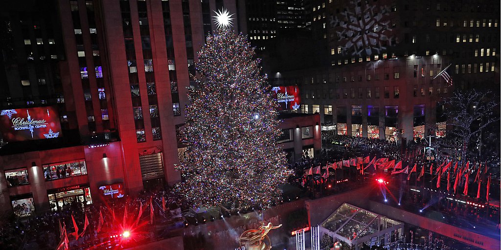 Singers gather on a stage beneath the Rockefeller Center Christmas Tree after the 77-foot high tree was illuminated in the 87th annual tree lighting ceremony, Wednesday, Dec. 4, 2019, in New York. (AP Photo/Kathy Willens)
