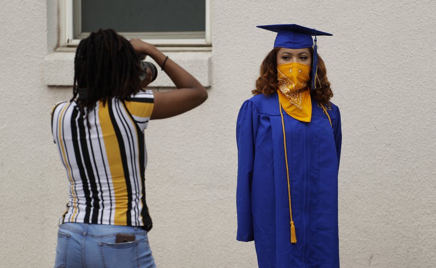 AP Anderson High School senior Teyaja Jones, right, poses in her cap and gown and a bandana face cover, Tuesday, May 5, 2020, in Austin, Texas. Texas  stay-at-home orders due to the COVID-19 pandemic have expired and Texas Gov. Greg Abbott has eased restrictions on many businesses that have now opened, but school buildings remain closed. (AP Photo/Eric Gay) Color