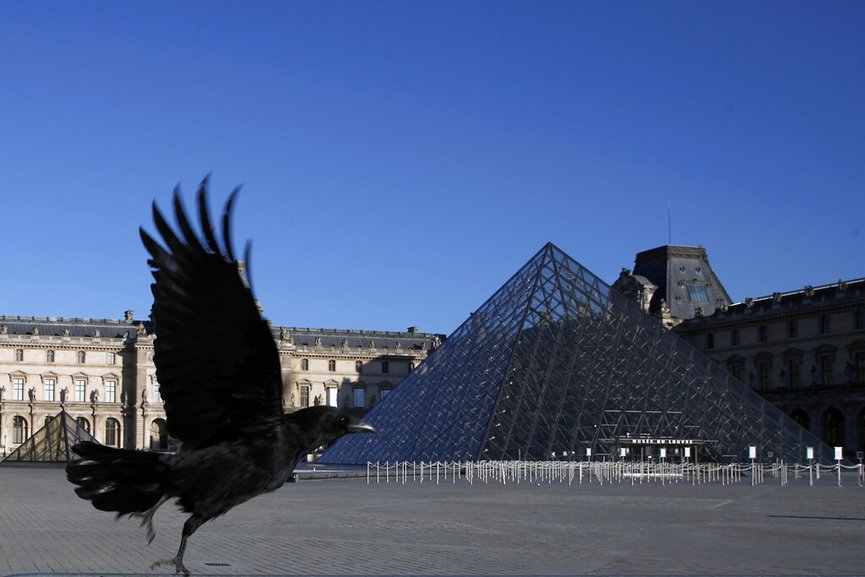 AP FILE - In this Monday, March 30, 2020 file photo, a black crow flies over in the deserted Louvre museum courtyard in Paris. The European Union unveiled Wednesday May 13, 2020, its plan to help confinement-tortured citizens across the 27 nations salvage their summer vacations after months of coronavirus lockdown and resurrect Europeβ€™s badly battered tourism industry. (AP Photo/Francois Mori, File)