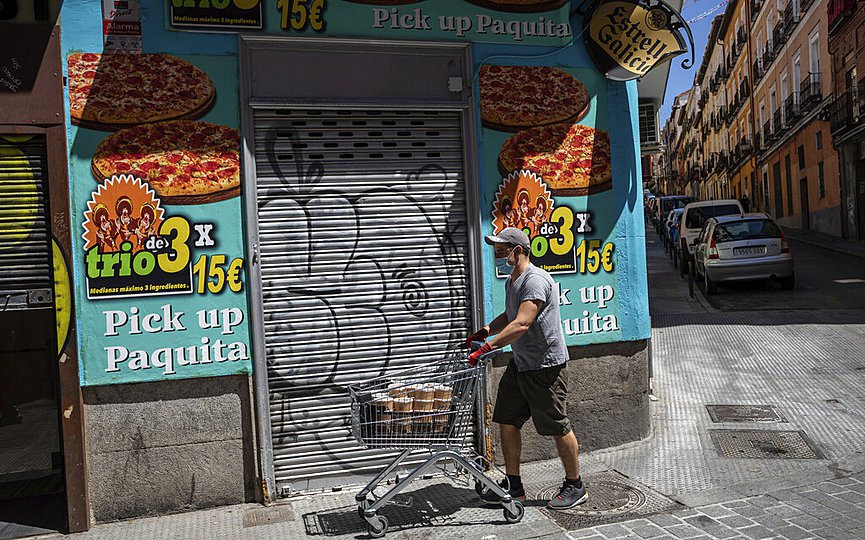A volunteer pushes a shopping cart full of food rations to be later distributed among hundreds of people at risk of social exclusion in Madrid, Spain, Tuesday, May 19, 2020.  (AP Photo/Bernat Armangue)