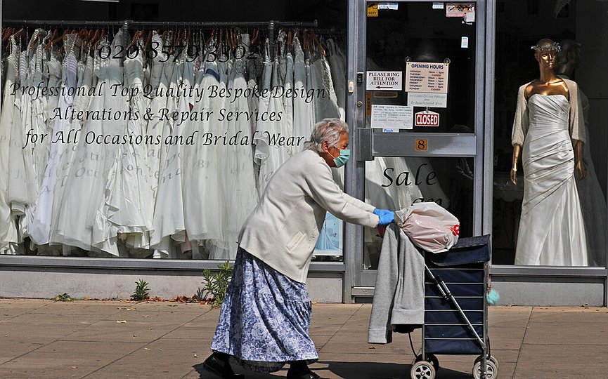 A woman walks past a Wedding dress shop in London, Tuesday, June 9, 2020, where bride dresses pile unused in the shop window. (AP Photo/Frank Augstein)