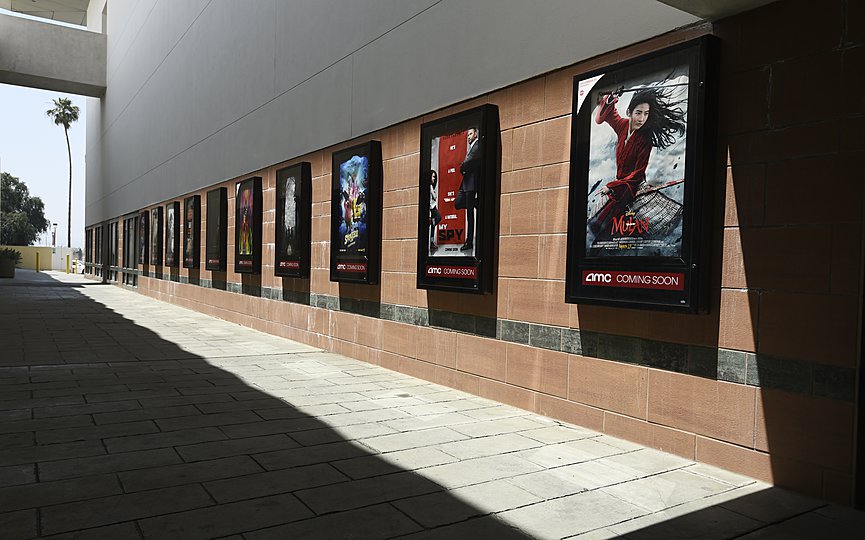 FILE - Posters for upcoming movies are displayed in an empty corridor at the currently closed AMC Burbank Town Center 8 movie theaters complex on April 29, 2020, in Burbank, Calif. (AP Photo/Chris Pizzello, File)