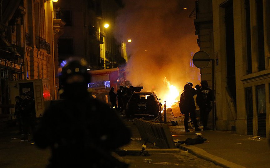 French police officers watch a car burning near the Champs-Elysee avenue following incidents after the Champions League soccer final match between PSG and Bayern Munich which is played in Lisbon, Portugal, Sunday Aug. 23, 2020 in Paris. Bayern Munich won 1-0. (AP Photo/Michel Euler)