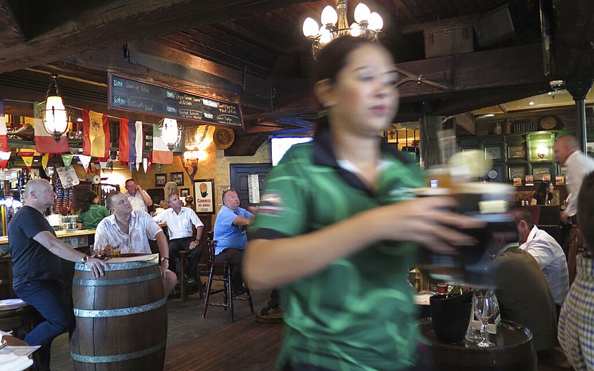 FILE - In this June 22, 2016 file photo, a waitress serves customers beer at a restaurant in Dubai, United Arab Emirates. (AP Photo/Kamran Jebreili, File)