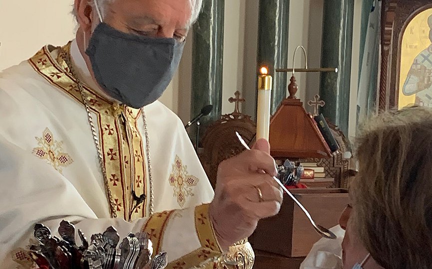 The presiding priest of the Dormition of the Virgin Mary in Southampton New York Protopresbyter of the Ecumenical Throne Fr. Alexander Karloutsos offers Holy Communion to the faithful using multiple spoons. (Photo provided by Dormition of the Virgin Mary in Southampton)