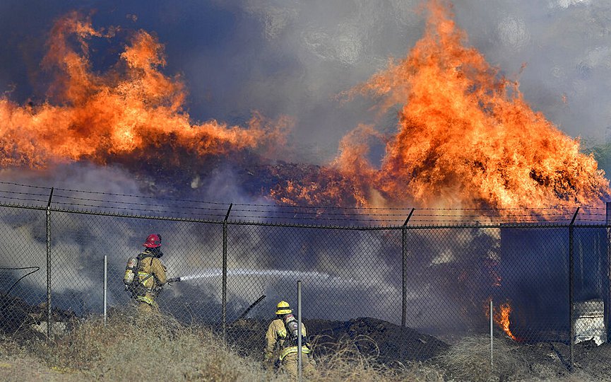Firefighters battle a mulch and pallet fire burning out of control, fanned by Santa Ana winds in and around a recycling yard near Wilson Street and Fleetwood Drive in Riverside, Calif., Thursday, Dec. 3, 2020. (Will Lester/The Orange County Register via AP)