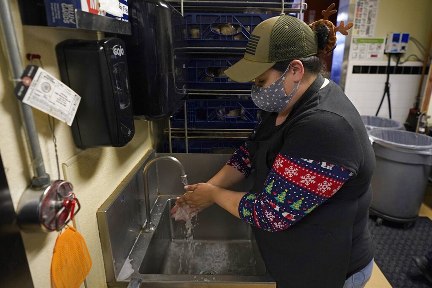 Elaine Honeycutt washes her hands while working at the San Francisco Deli in Redding, Calif., Thursday, Dec. 3, 2020. (AP Photo/Rich Pedroncelli