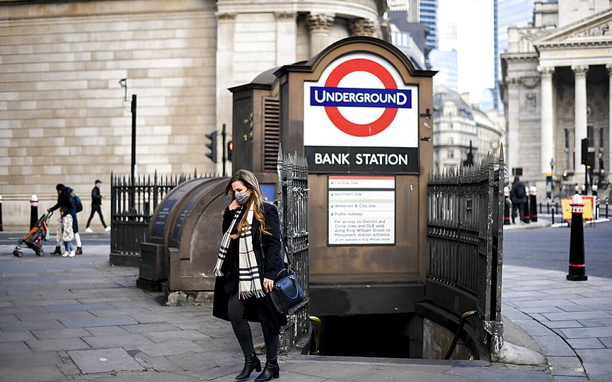 A woman wears a face mask as she steps out of Bank underground station, in London, Tuesday, Dec. 8, 2020. (AP Photo/Alberto Pezzali)