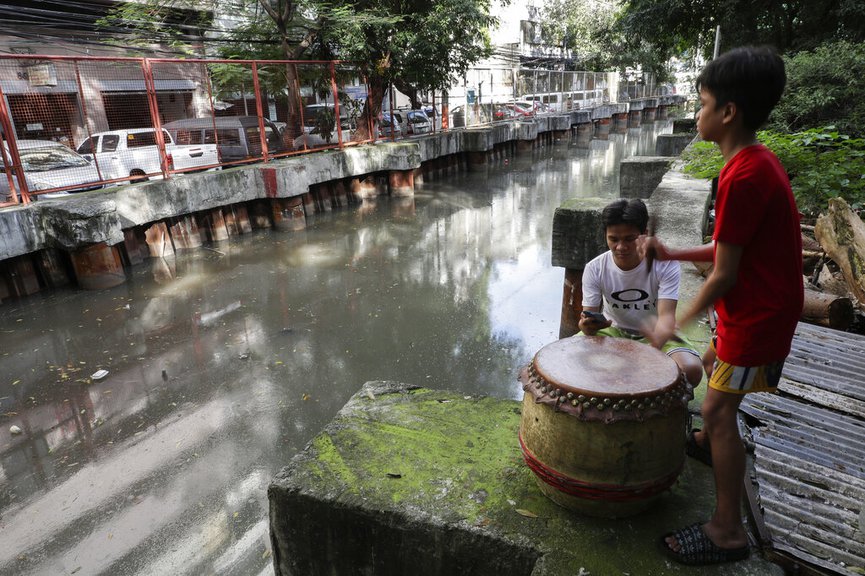 Carlo Sicat, left, uses his smartphone to record the drum beat while his son Gian practices after a year of almost not playing due to pandemic restrictions at a creekside slum at Manila s Chinatown, Binondo, Philippines on Feb. 4, 2021. (AP Photo/Aaron Favila)