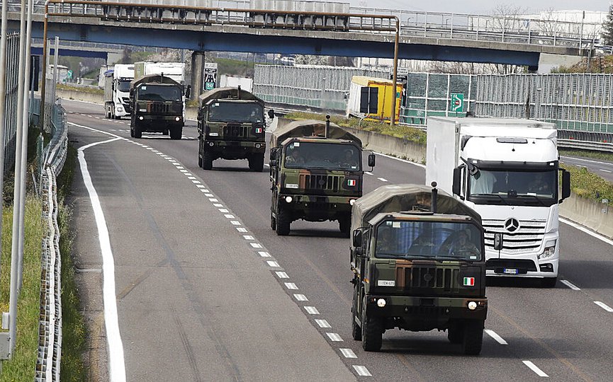 FILE - In this March 26, 2020 file photo, military trucks moving coffins of deceased people line up on the highway next to Ponte Oglio, near Bergamo, one of the areas worst hit by the coronavirus infection, on their way from Bergamo cemetery to a crematory in some other location as the local crematory exceeded its maximum capacity. (AP Photo/Luca Bruno, File)