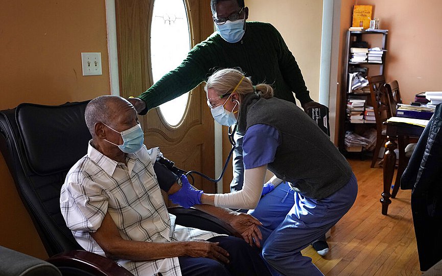 Edouard Joseph, 91, left, has his blood pressure taken by geriatrician Megan Young, right, as Joseph s son, Edouard F. Joseph, top, offers support after his father received a COVID-19 vaccination, Thursday, Feb. 11, 2021, at his home in the Mattapan neighborhood of Boston. (AP Photo/Steven Senne)