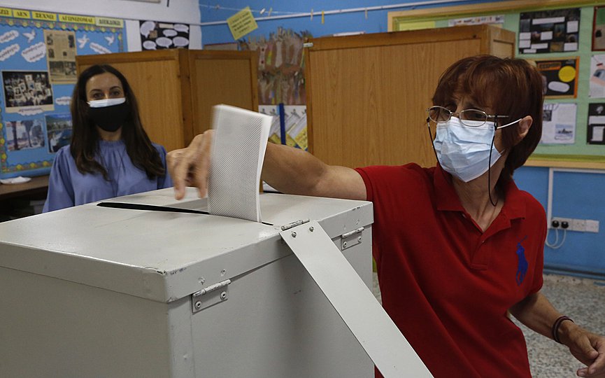 A woman wearing face protective mask casts her vote at a polling station during the parliamentary elections in Deftera, a suburb of capital Nicosia, Cyprus, Sunday, May 30, 2021. (AP Photo/Petros Karadjias)
