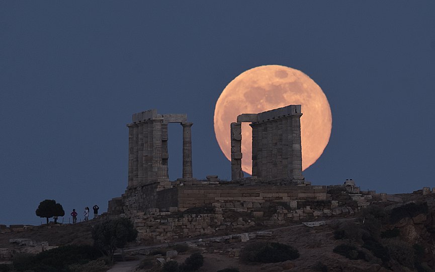 FILE - The full moon rises behind the columns of the ancient marble Temple of Poseidon at Cape Sounion, about 70 Km (45 miles) south-southeast of Athens, on Tuesday , May 29, 2018. (AP Photo/Petros Giannakouris)
