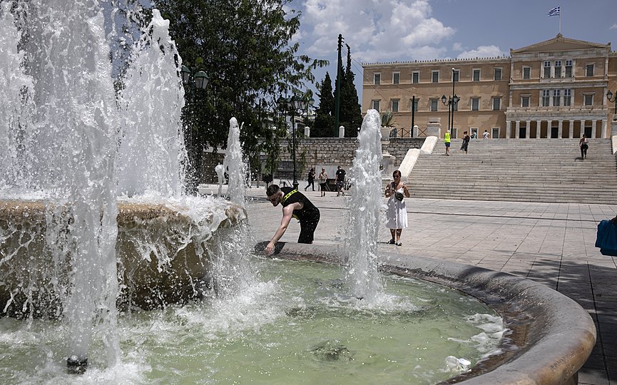 A man cools himself with water from a fountain during a hot day at central Syntagma square, in Athens, Saturday, June 26, 2021. (AP Photo/Yorgos Karahalis)