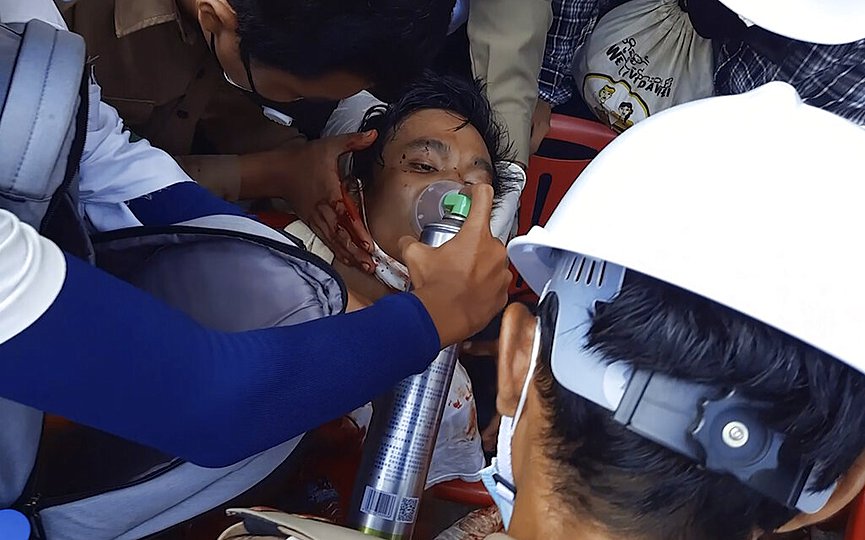 FILE - In this Sunday, Feb. 28, 2021 image from video provided by Dakkhina Insight, medics attend to a man who appeared to be wounded in his upper chest on a street in Dawei, Myanmar. (Dakkhina Insight via AP)