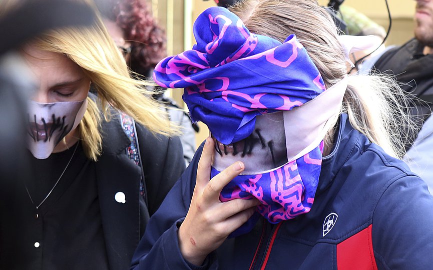 FILE - A 19-year old British woman, right, covers her face as she leaves from the Famagusta court after her trial, in Paralimni, Cyprus, Monday, Dec. 30, 2019. (AP Photo/Philippos Christou)
