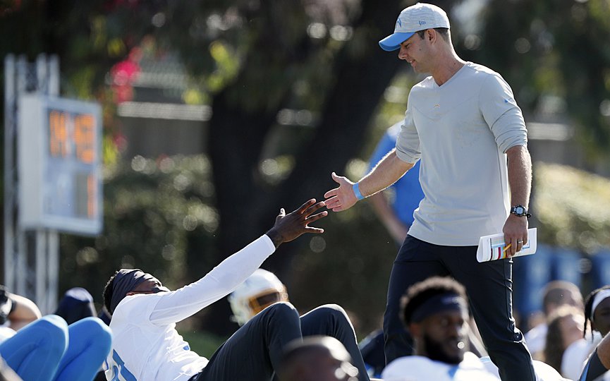 In this July 28, 2021 photo, Los Angeles Chargers head coach Brandon Staley greets wide receiver Mike Williams during practice at the NFL football team s training camp in Costa Mesa, Calif. As workers return to the office, friends reunite and more church services shift from Zoom to in person, this exact question is befuddling growing numbers of people: to shake or not to shake. (AP Photo/Alex Gallardo)
